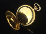 a close up of a gold pocket watch on a black surface