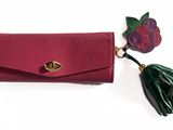 a close up of a red purse with a tassel on a white background