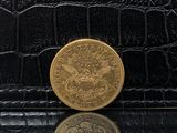 portefeuille en peau d'alligator noir avec une pièce de monnaie en or sur le dessus