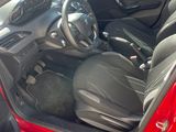 une voiture rouge dont la portière est ouverte sur un parking
