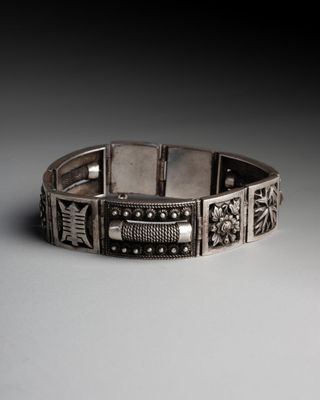 a close up of a silver bracelet on a white surface
