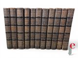 six old books are lined up in a row on a white surface