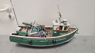 a model of a green and white boat sitting on the floor