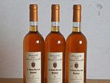 trois bouteilles de vin posées sur une table en bois, à côté d'une bouteille de vin