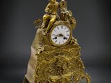 une horloge en or posée sur un bloc de marbre