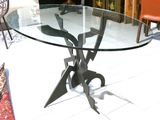 a glass table with a metal base on a tile floor