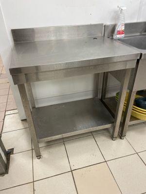 a stainless steel table in a kitchen with a sink and a dishwasher