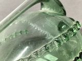 a green glass bottle with a handle on a table
