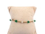 a close up of a pillow on a pillow with a green beaded bracelet