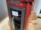 un poêle rouge posé sur une palette devant un réfrigérateur
