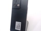 a black cell phone sitting on a stand on a white surface