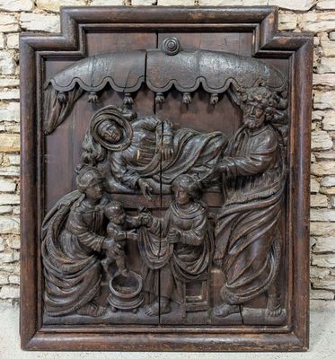 un relief en bois représentant la Nativité de Jésus et de Marie sur un mur de pierre