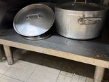 several pots and pans are sitting on a metal shelf in a kitchen