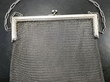 an old silver mesh purse on a table with a chain around it