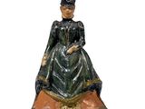 figurine représentant une femme vêtue d'une robe verte et d'un chapeau noir