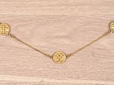 a gold plated necklace with three discs on a gold chain