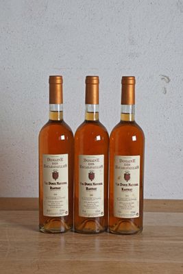 trois bouteilles de vin posées sur une table en bois, à côté d'une bouteille de vin