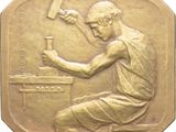 an image of a gold medal depicting a man with a hammer in his hand