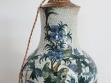 un vase bleu et blanc posé sur une table sur laquelle se trouve une lampe
