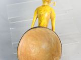 une petite figurine jaune posée sur un bol en bois