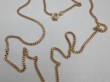 gros plan d'un collier en or avec une chaîne sur une surface blanche