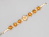a gold bracelet with orange stones and diamonds on a white background