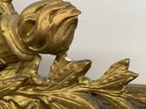 a gold statue of a bird on a leafy branch