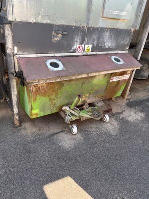 a green dumpster sitting on the side of the road