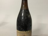 an old bottle of wine sitting on top of a white table