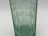 a green glass bottle with writing on it on a white surface