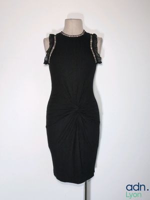 La robe est noire et présente un décolleté orné de perles.