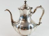 an antique silver tea pot with a handle on a white background
