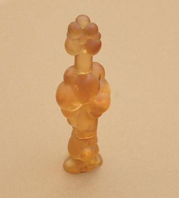 une petite figurine en verre représentant une femme avec une fleur sur la tête