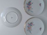 three plates with flowers on them on a white table