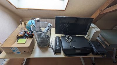 un bureau sur lequel se trouvent un ordinateur, une imprimante et d'autres objets