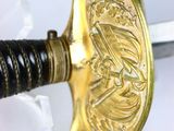 a gold sword with a black handle on a white surface