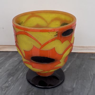 un vase jaune et orange posé sur un socle noir