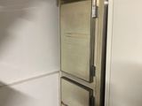 a refrigerator in the corner of a room with a door open