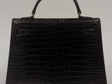 a black crocodile skin handbag on a white background