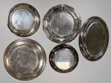 six silver plates are arranged on a white surface