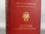an old red book with a gold emblem on the cover
