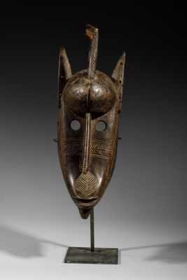 a wooden mask on a stand on a white surface