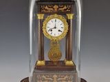 une petite horloge sous un dôme de verre sur une table