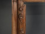 an antique wooden fireplace surround with carvings on the top of it