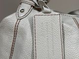 a close up of a white purse with a tag on it