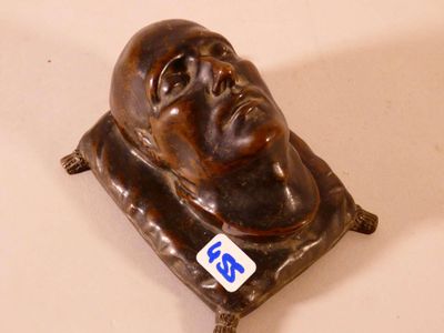 une statue représentant un homme assis sur un coussin posé sur une table