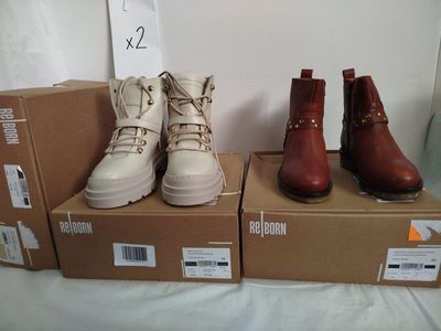 trois paires de bottes sont posées sur des cartons, sur un lit