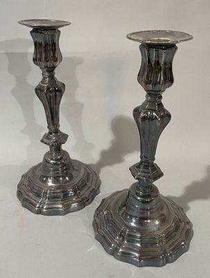 deux chandeliers en argent posés sur une surface blanche