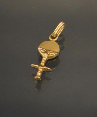 a close up of a gold plated key charm on a black surface