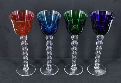 quatre verres à vin de couleurs différentes sont alignés sur un fond noir